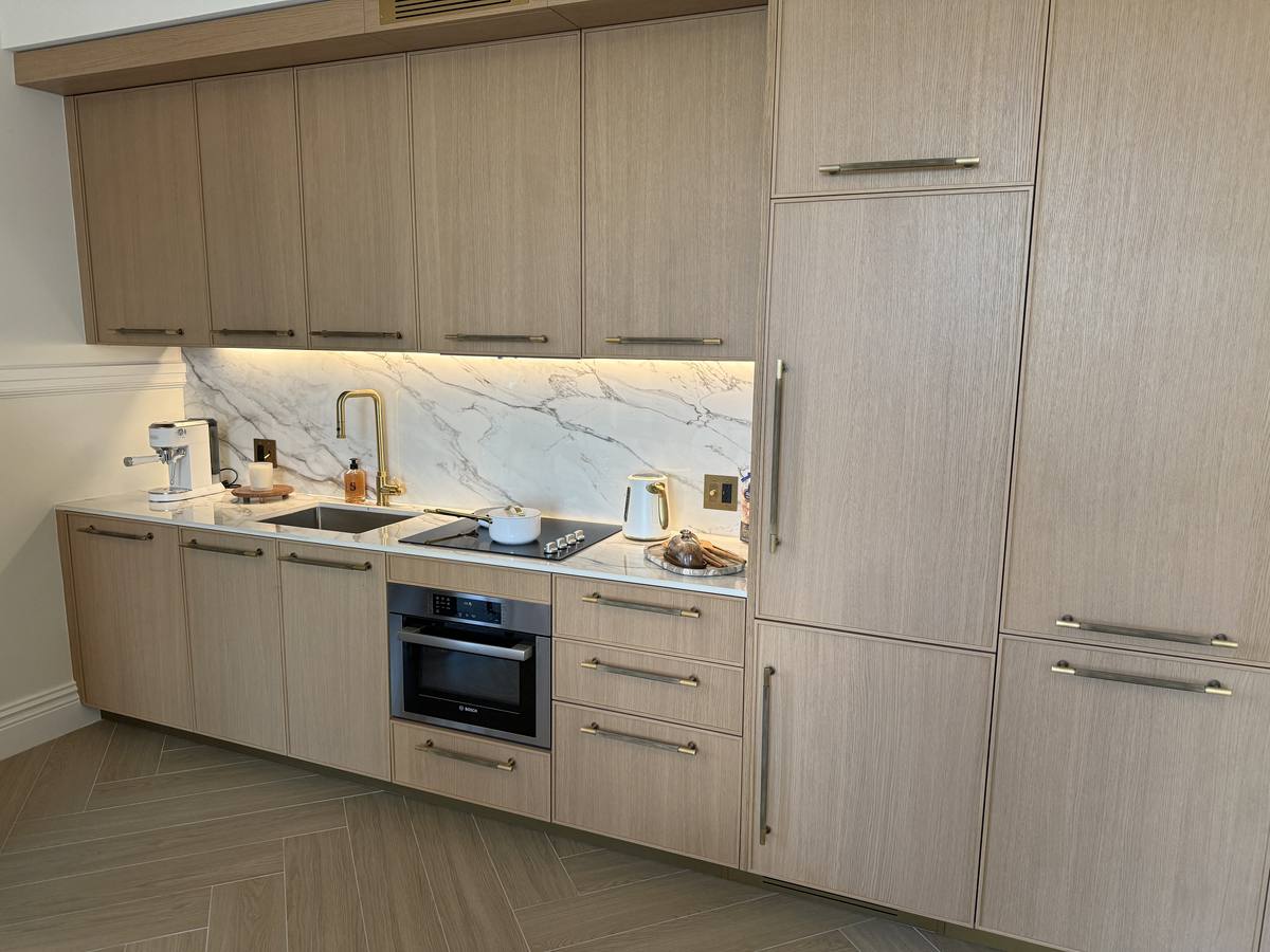 Cocina de Casa Tua Residences con gabinetería de madera clara, encimera de mármol Calacatta y herrajes de bronce